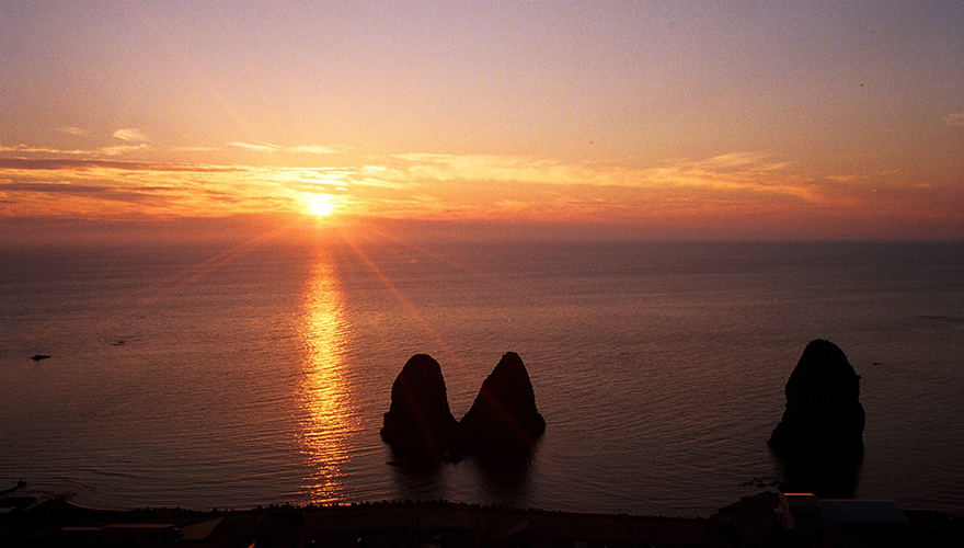 日本海に沈む夕陽と三本杉岩